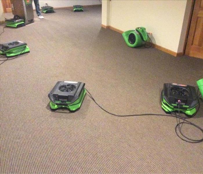 Dry grey carpet with green air movers spread out on the floor.