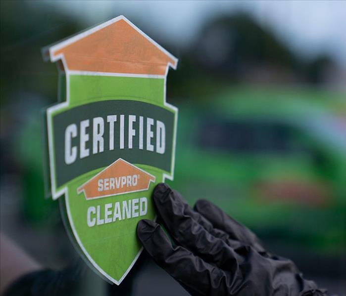 Certified: SERVPRO Cleaned sticker being placed on a glass door.